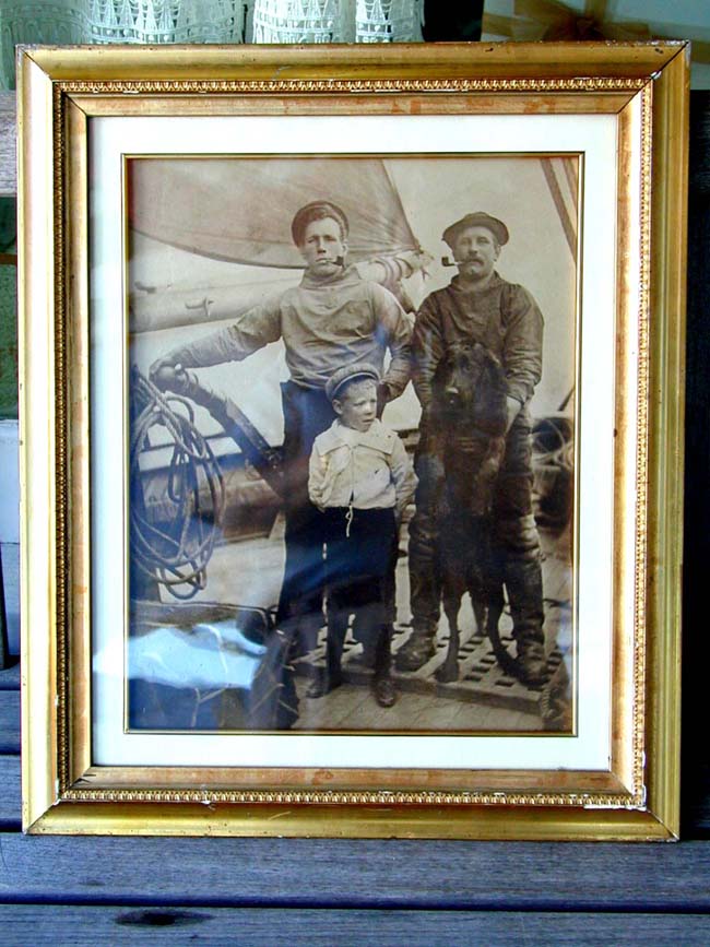 A Late 19th century Photograph of Two Sailors, a Boy and a Labrador Retriever at the Helm of a Ship