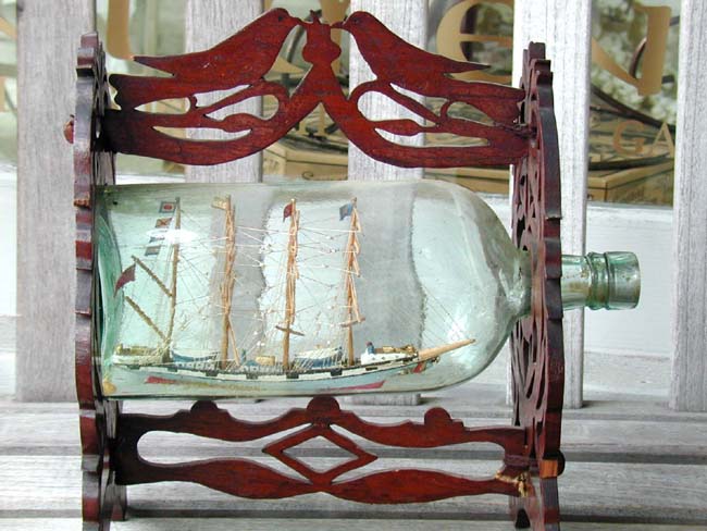 A Nice 19th century Ship-in-a Bottle in an elaborately carved fretwork frame circa 1875.