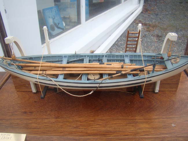 A very fine whaleboat model secured by davits to the hull of a whaling ship