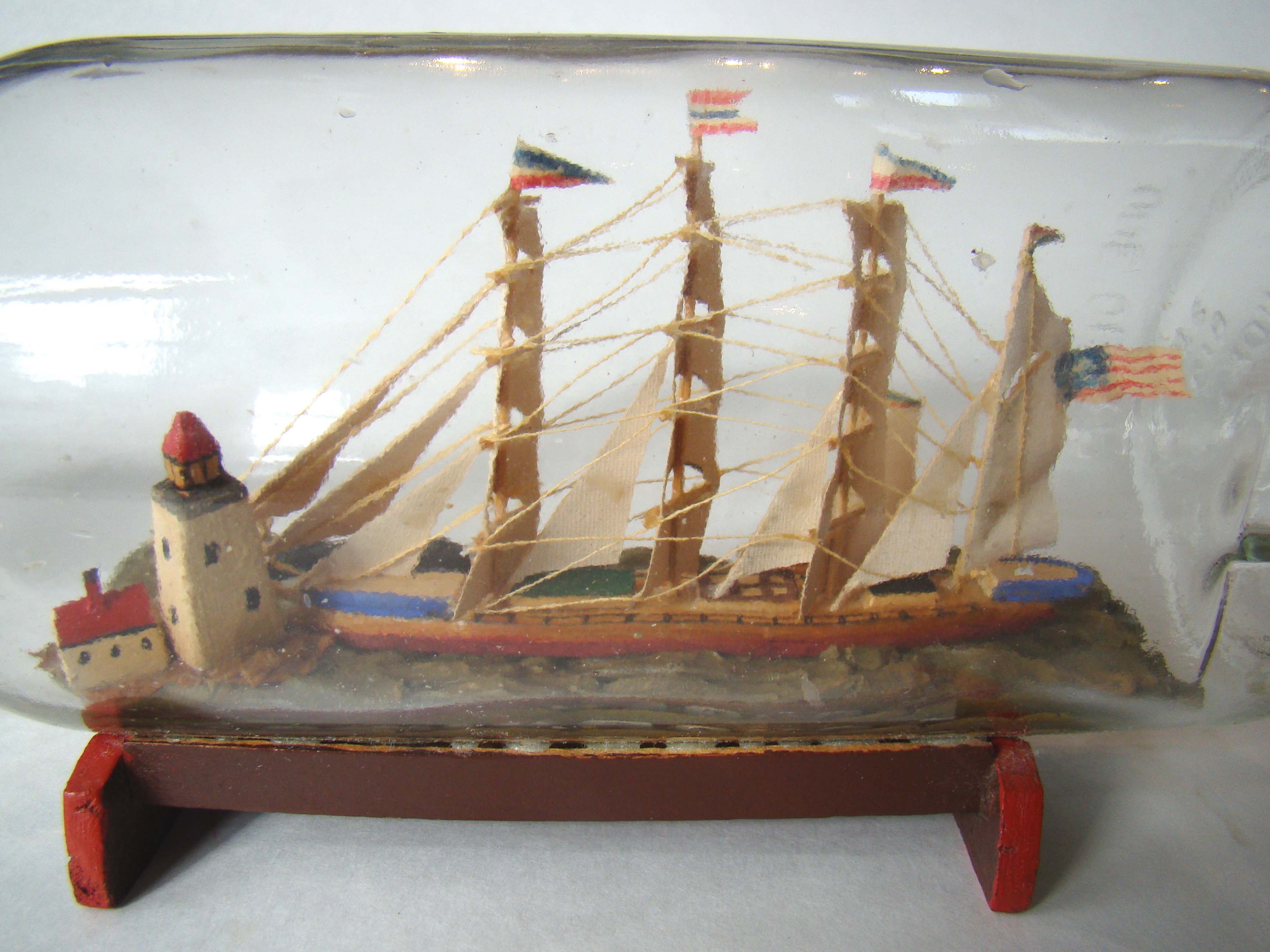 A fine early 20th century ship-in-a bottle featuring two ships approaching a lighthouse