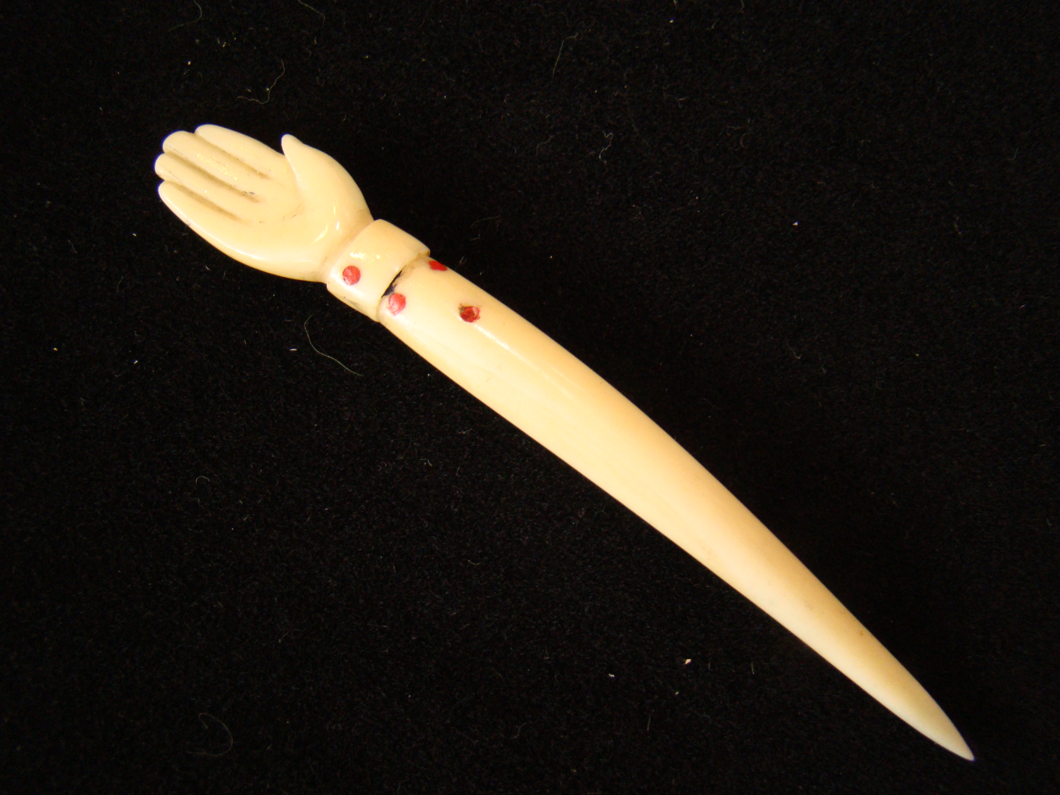 An unusual 19th century sailor-made whalebone bodkin with open hand knob and inlaid with red dots