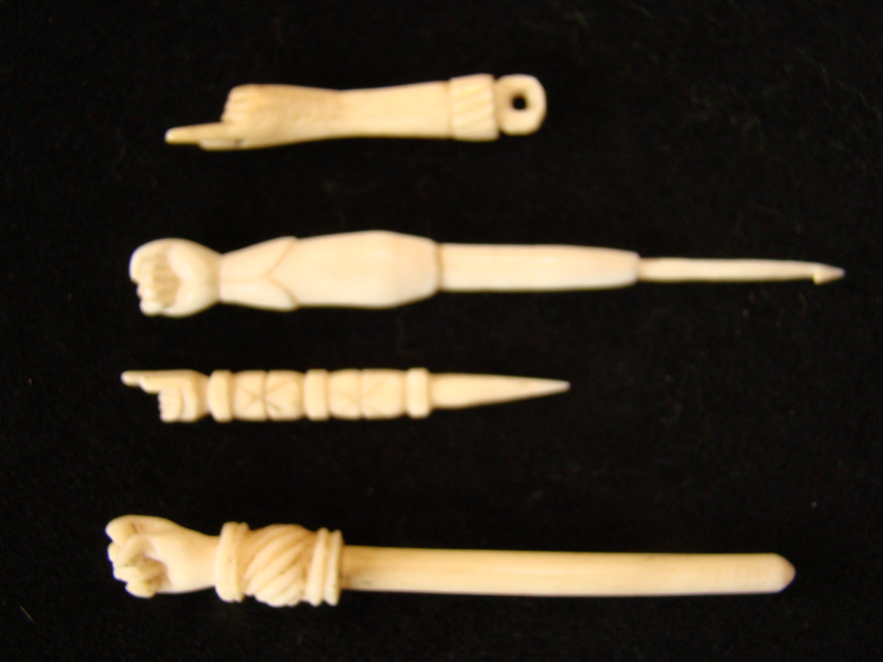 A fabulous group of four 19th century sailor made whalebone bodkins each having a hand or fist knob