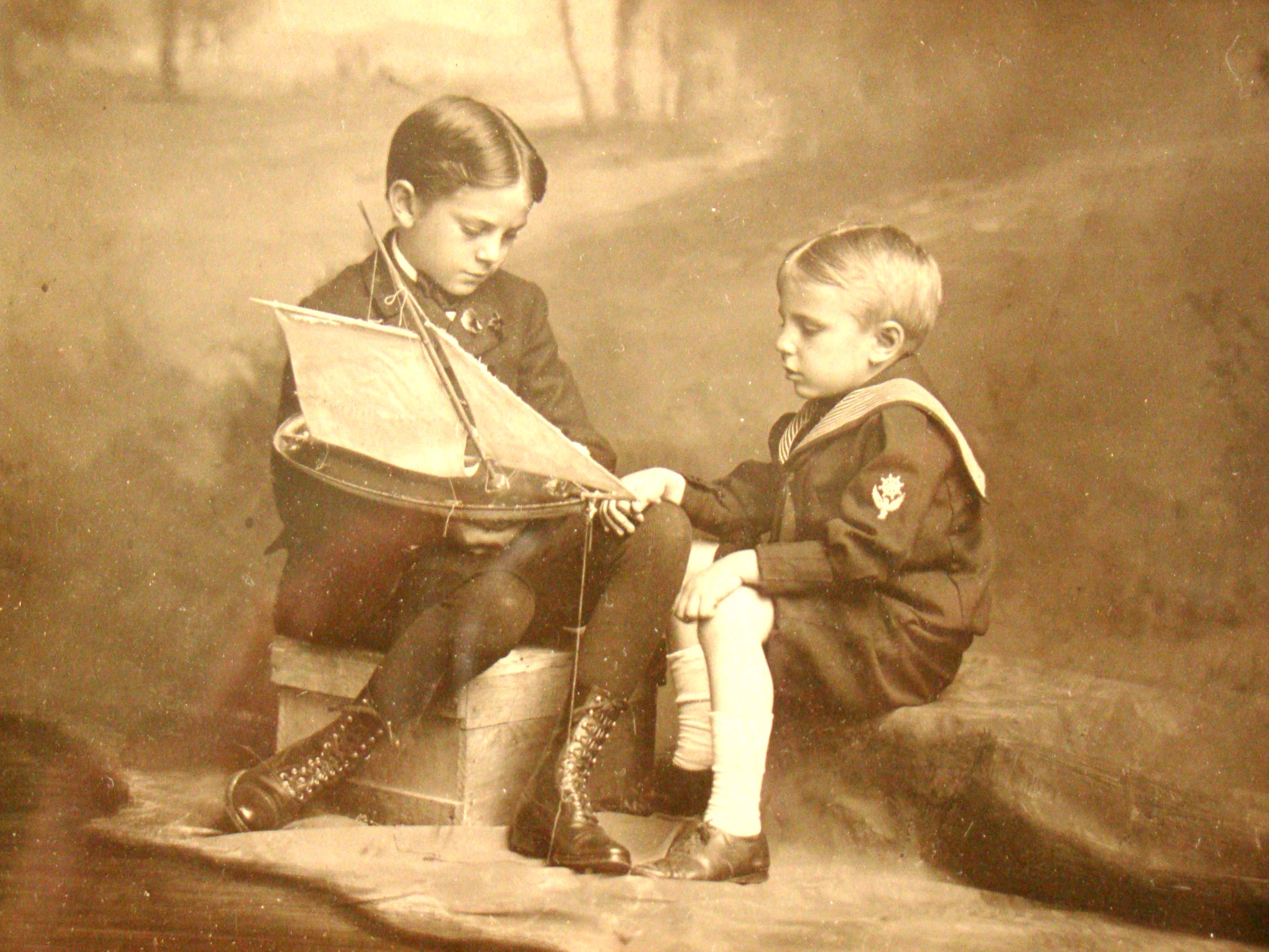 A fine vintage photo of two young boys examining a model pond boat circa 1900