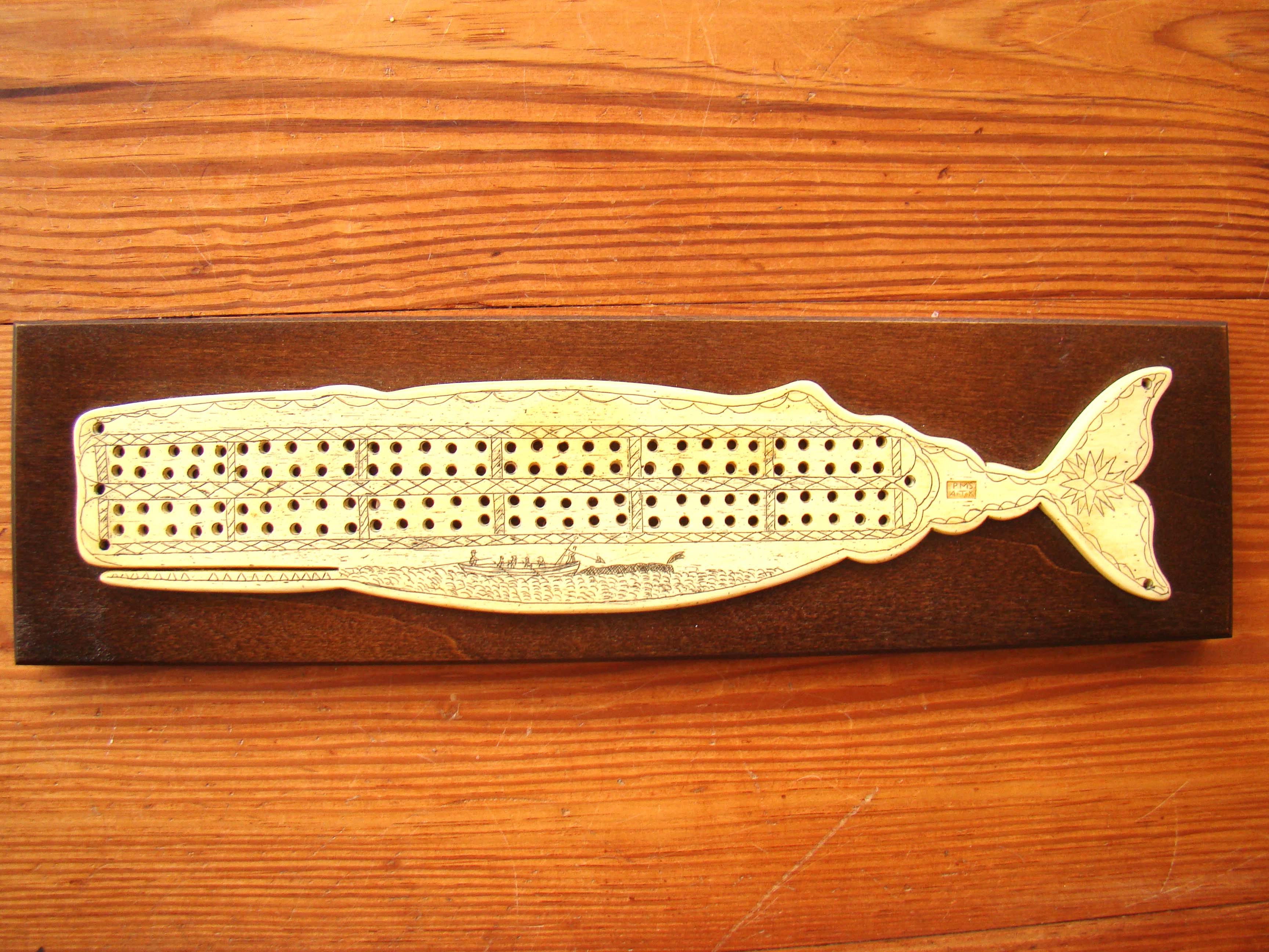 A faux scrimshaw sperm whale cribbage board copied from the original in a New England Museum