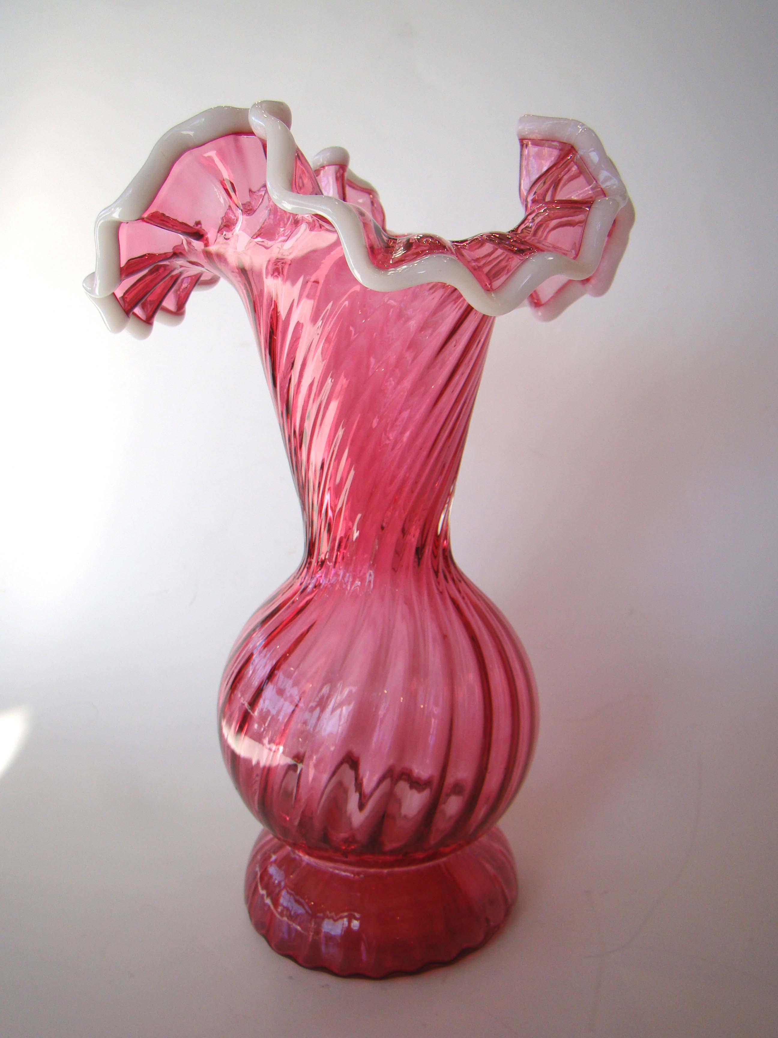 A vintage cranberry swirl glass vase with white petal edges