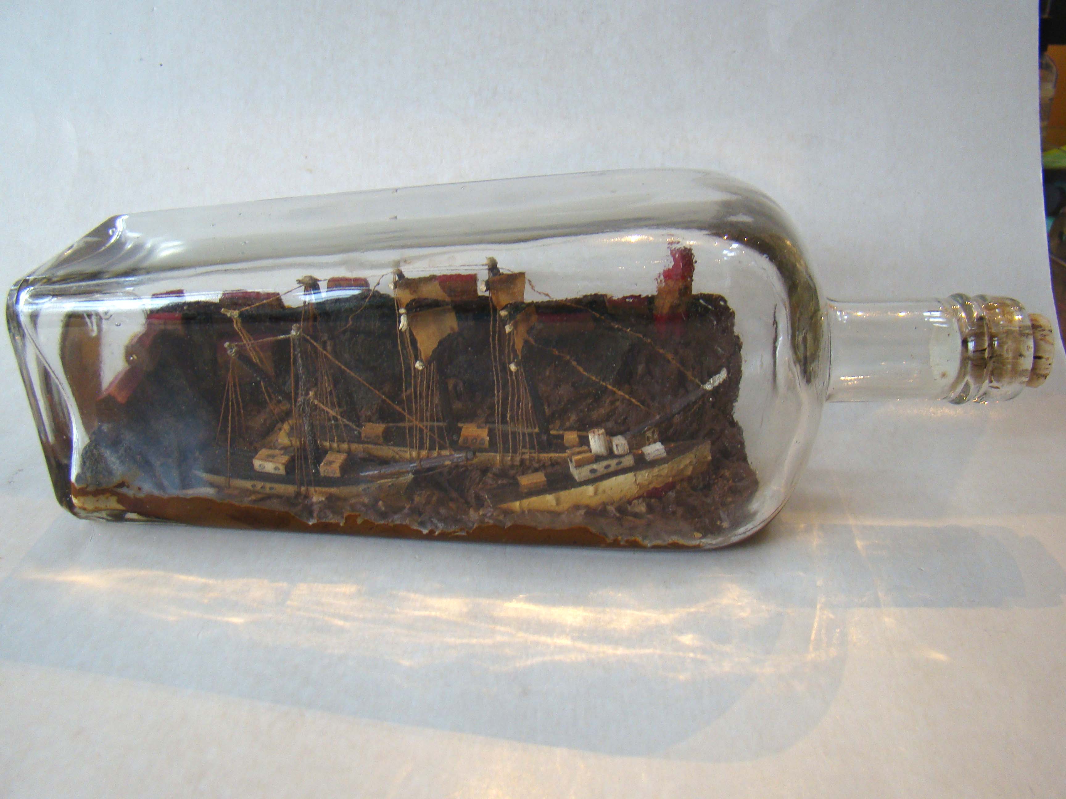 A fine early 20th century fully rigged ship-in-a bottle with two other smaller ships in the foregrou