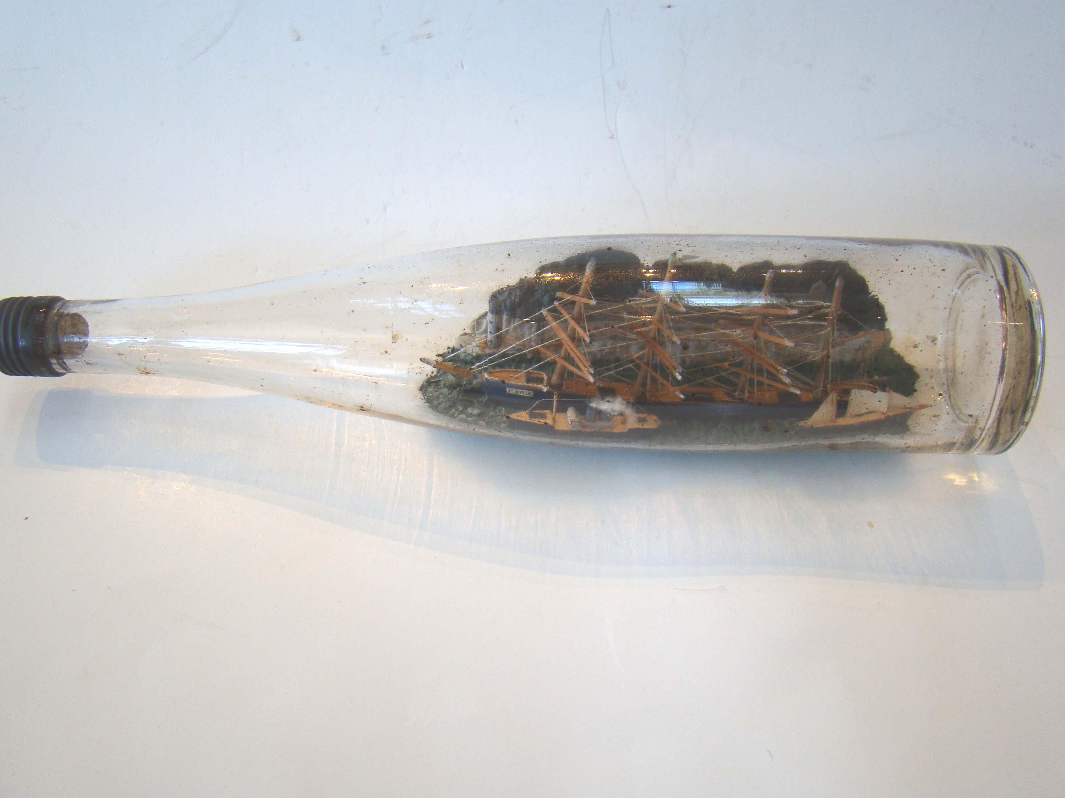 A fine vintage four-masted ship-in-a bottle circa 1910-1920 with two smaller ships in the foreground.
