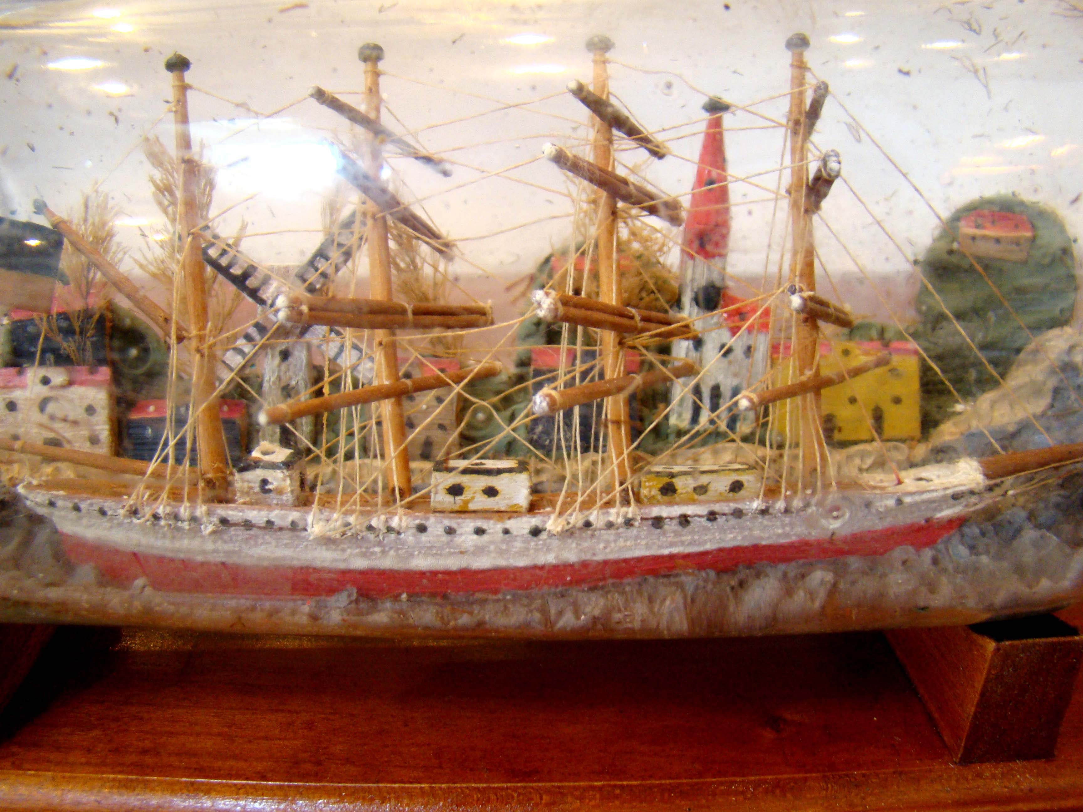 A fine vintage four-masted ship-in a bottle flying the American flag  with a charming village in the background circa 1900-1920   — image 2