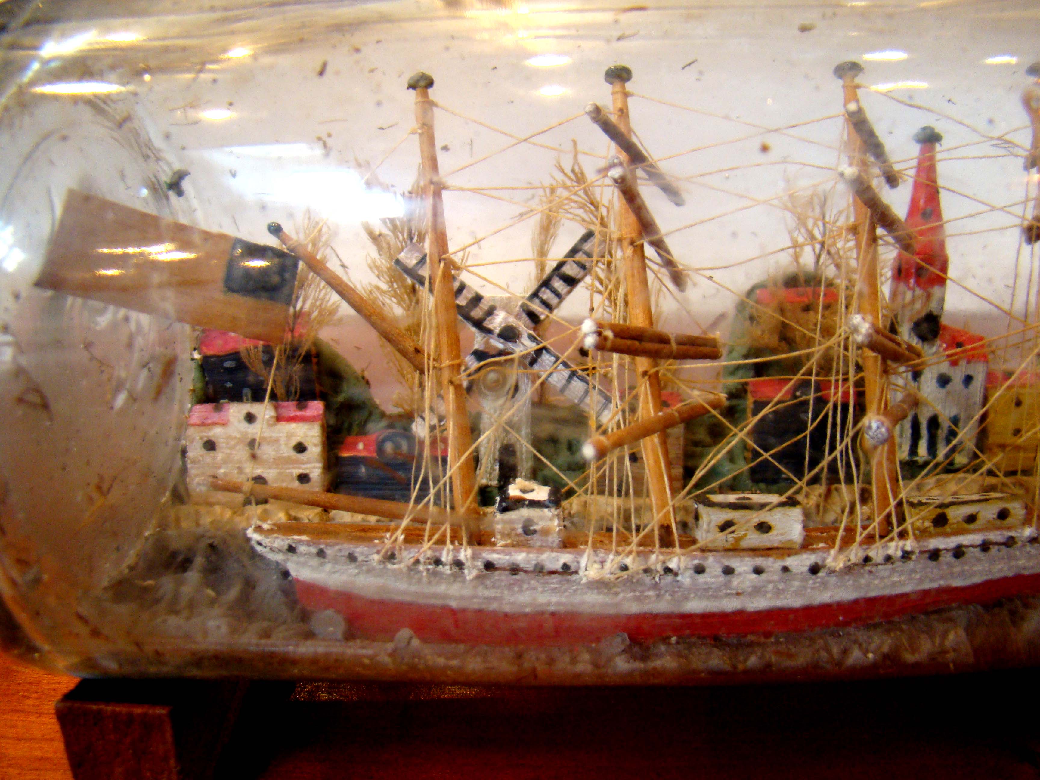 A fine vintage four-masted ship-in a bottle flying the American flag  with a charming village in the background circa 1900-1920   — image 4