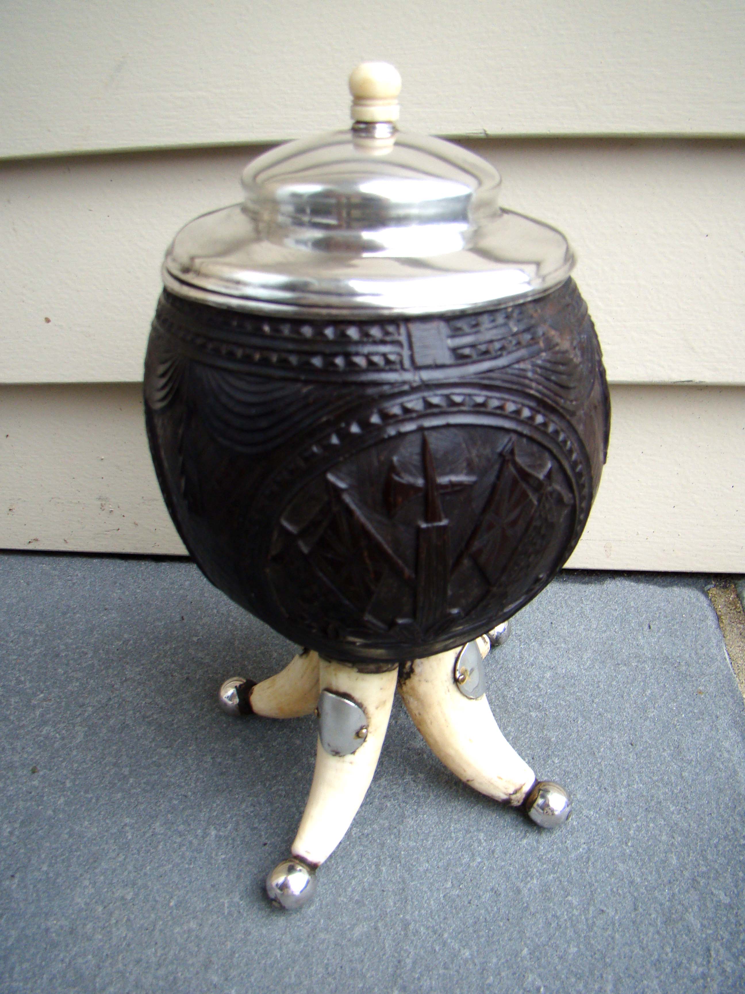 A fine and rare early 19th century silver mounted carved coconut shell covered cup on four whale's teeth