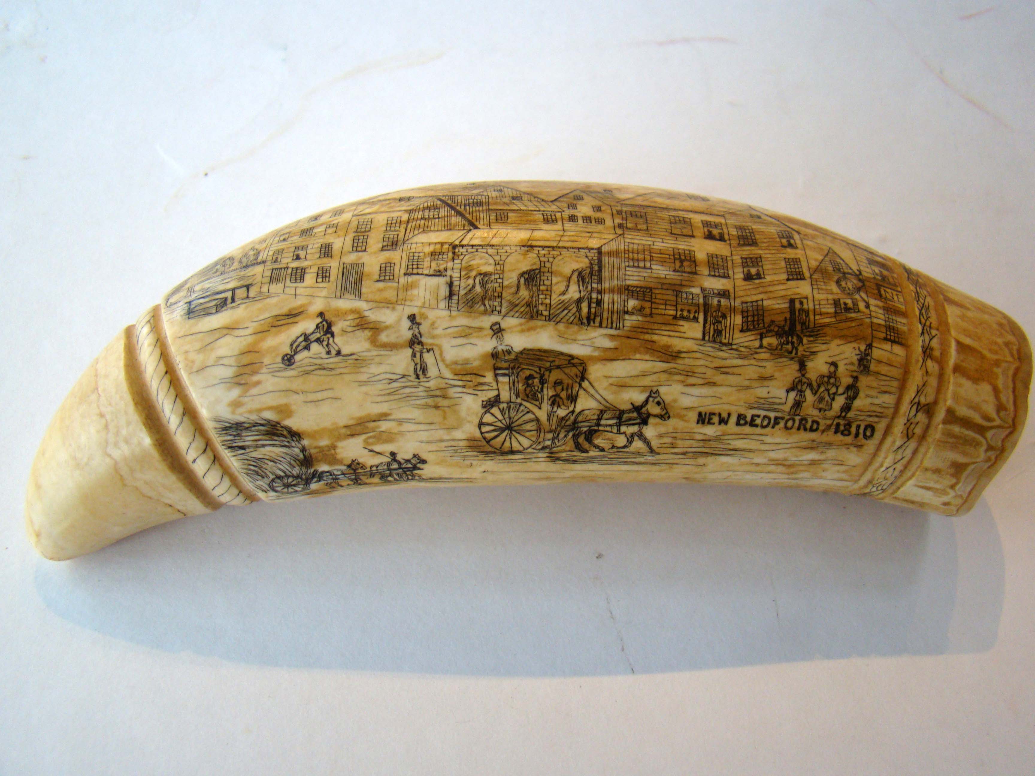 A carved and engraved whale's tooth depicting "New Bedford in 1810". 20th century
