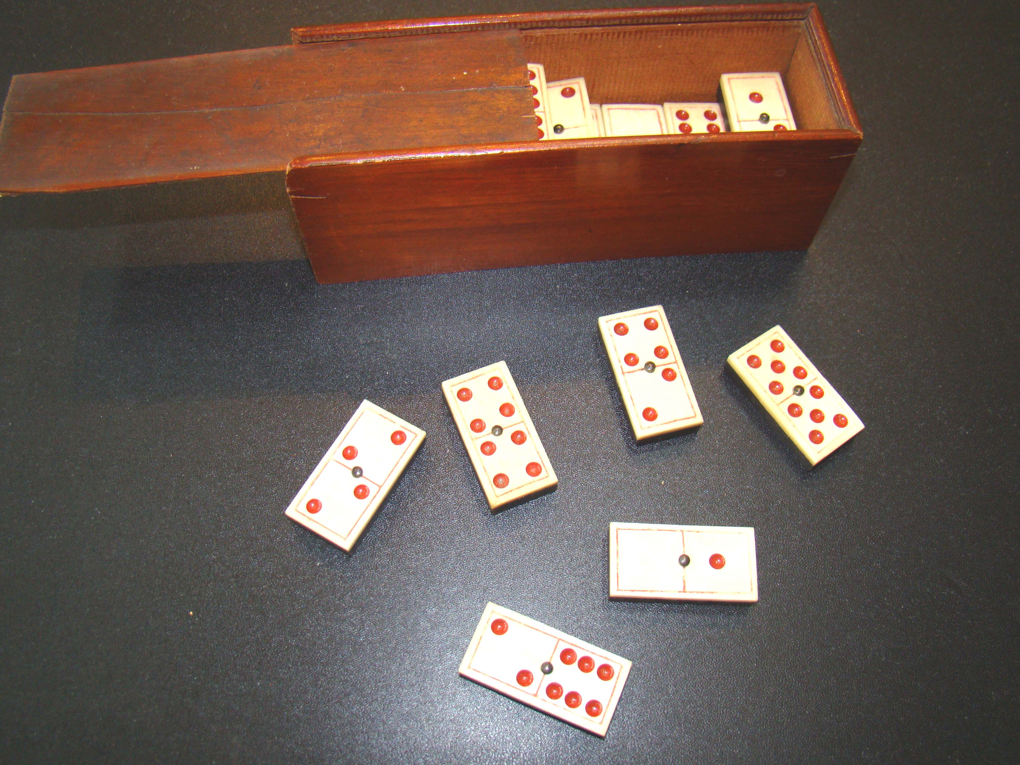 A fine and complete set of 28 bone and ebony dominoes with red dots and borders circa 1880