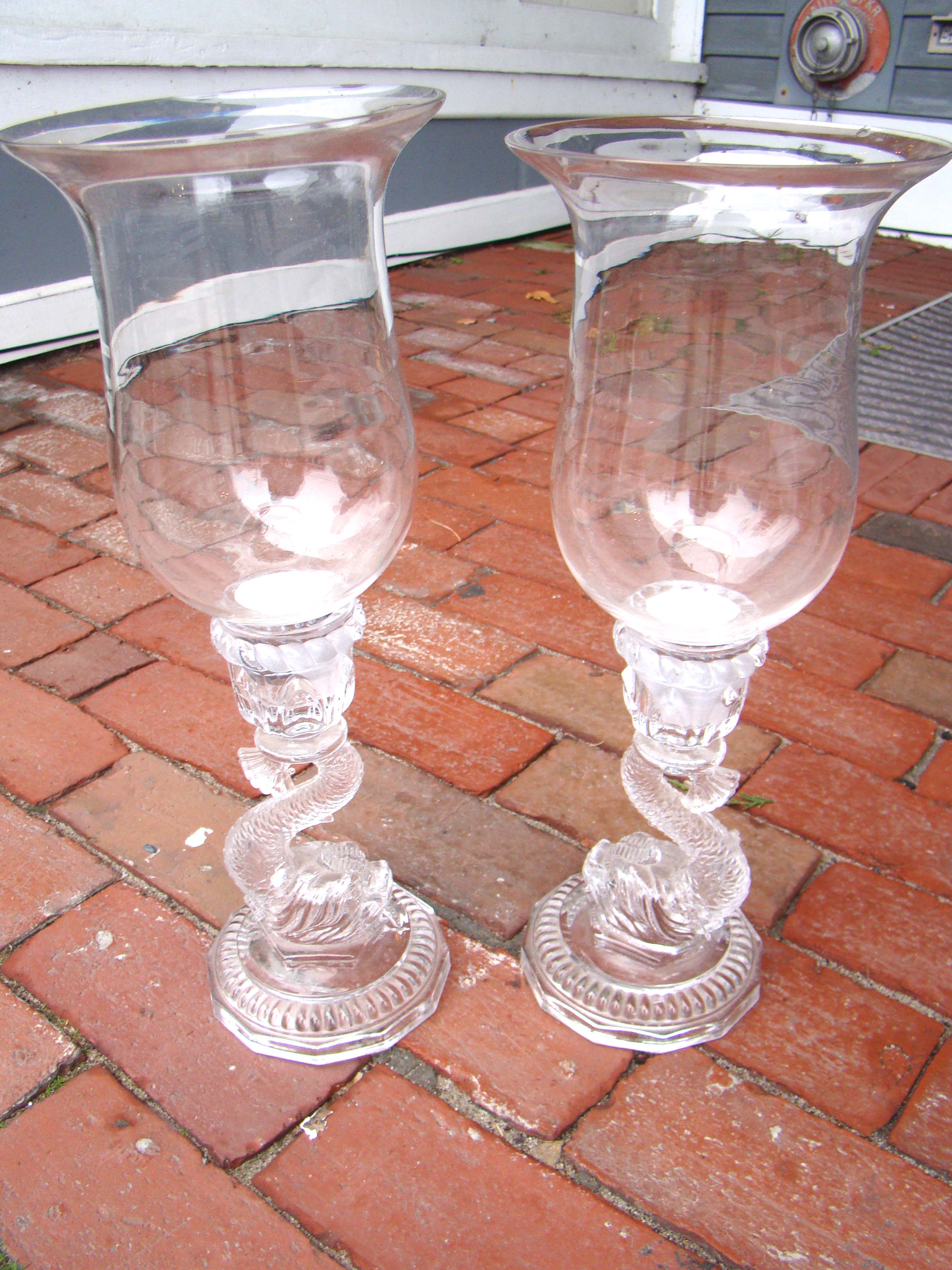 A pair of Dolphin form glass candlesticks with hurricanes