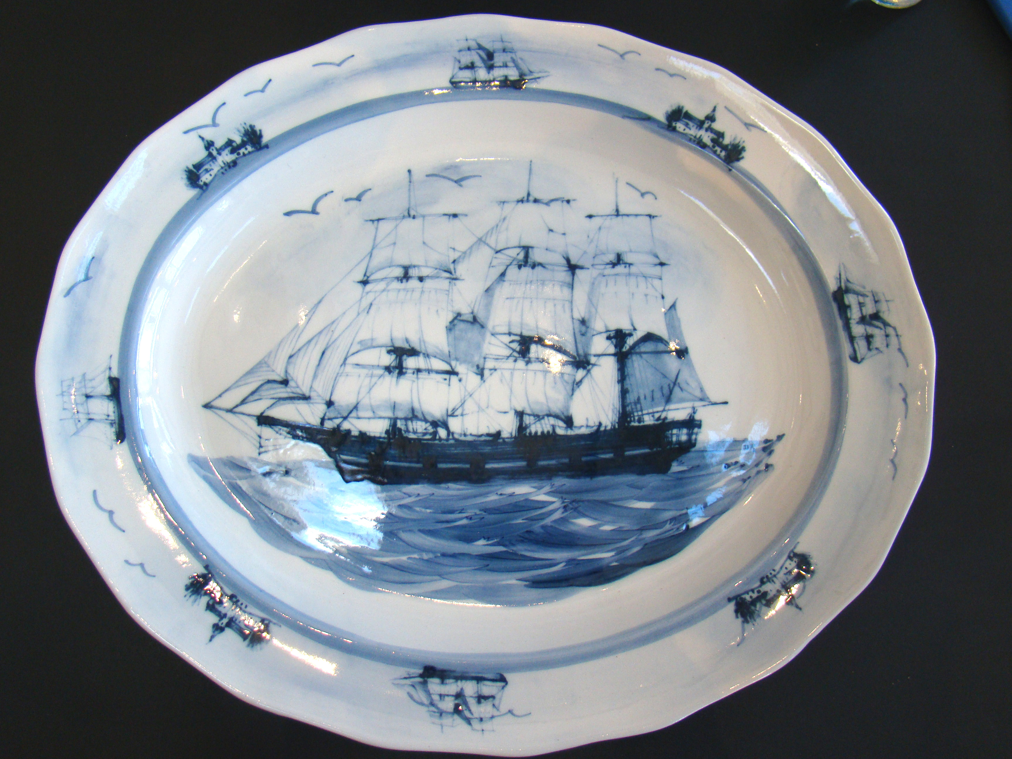 A  beautiful contemporary serving platter featuring a sailing ship with nautical vignettes around the border
