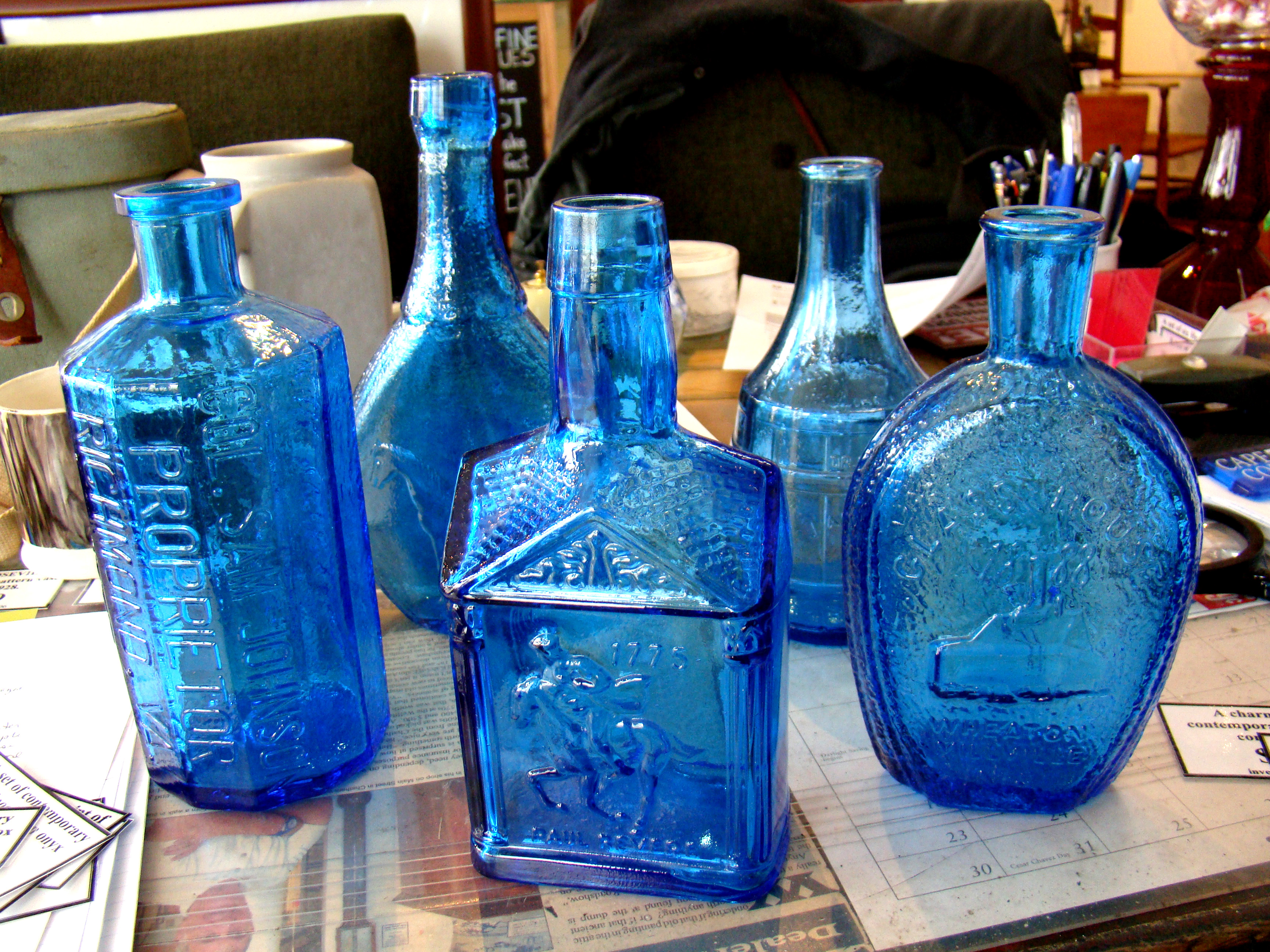 A collection of five reproduction aqua blue glass flasks and bottles