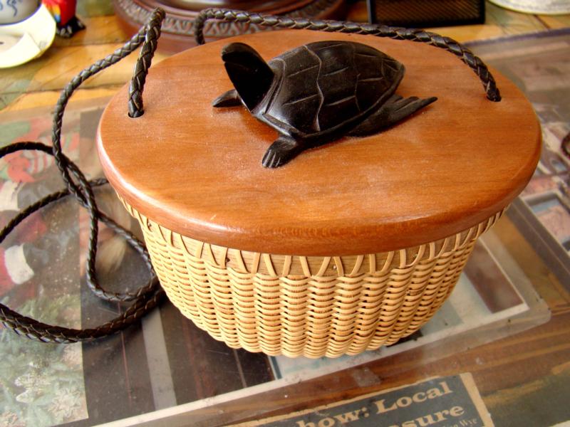 An oval Nantucket basket having a carved ebony  tortoise on the lid